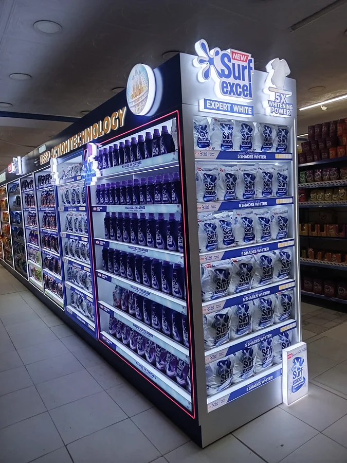 Illuminated Surf Excel Expert White end unit at the head of a laundry aisle